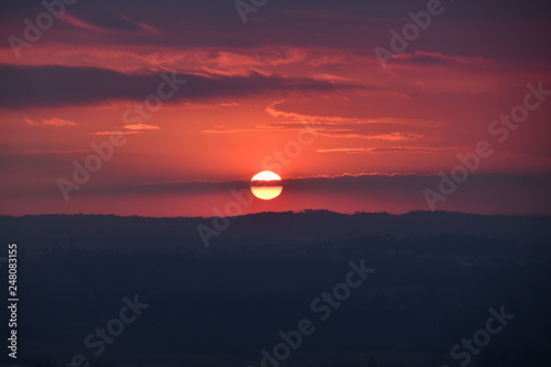 fiery sunset against a background of a provincial Italian town the sun is divided in half by clouds © Andrey