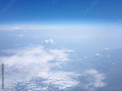 View from the high angle of the sky  clouds  fluffy  soft  space with shades of blue sky and earth background from above flying airplane window in bright morning sunrise 