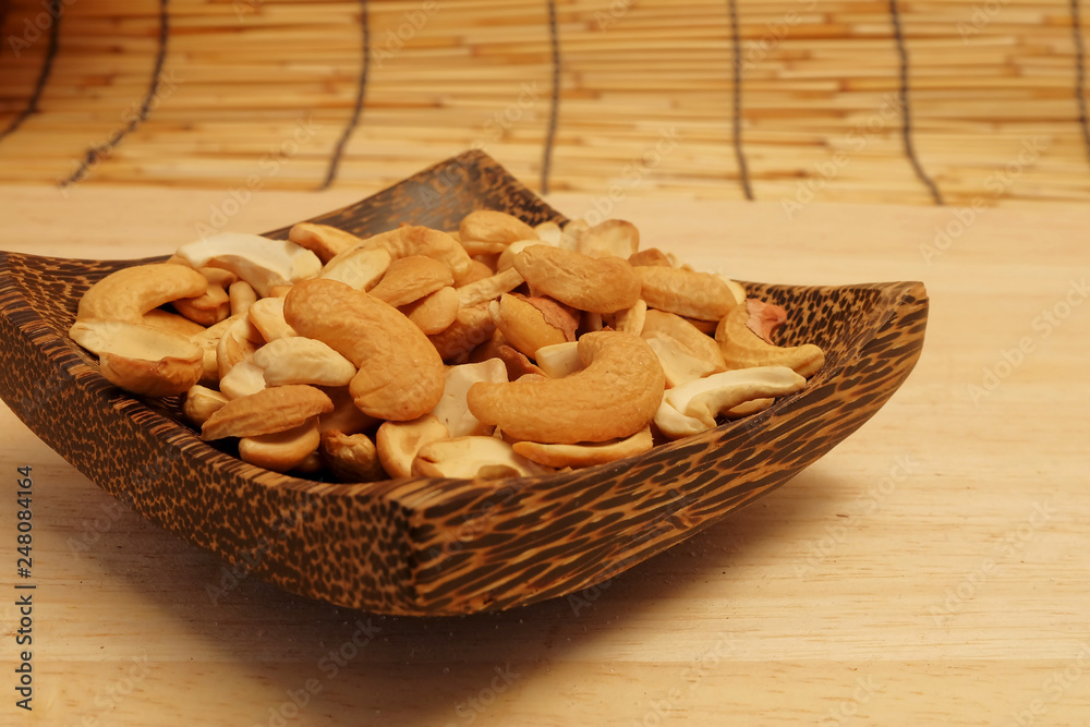 Dry roast Cashew nut in wood bowl on wood table and space for write wording, delicious snack and ingredient for making food, cookie, cake, served with coffee or tea for special celebration or party