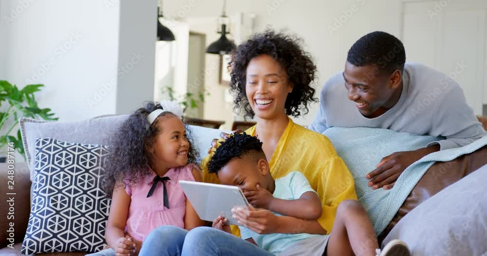 Front view of black family using digital tablet in living room at home 4k