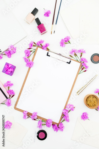 Blogger workspace with clipboard, notebook, pink flowers and accessories on white background. Flat lay, top view.