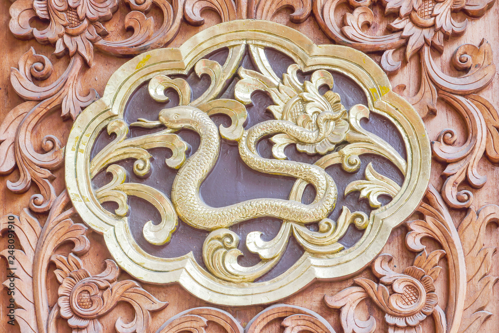 Traditional Thai style wood carving Snake of 12 Zodiac,on the wall of temple in Thailand