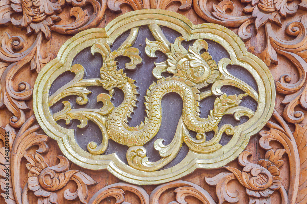 Traditional Thai style wood carving serpent of 12 Zodiac,on the wall of temple in Thailand