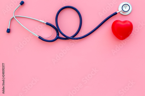 Heart health, health care concept. Stethoscope near rubber heart on pink background top view space for text