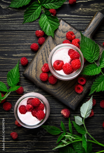 Raspberry smoothie in glass jars with fresh berry and yogurt on vintage wooden kitchen table background, flat lay, top view