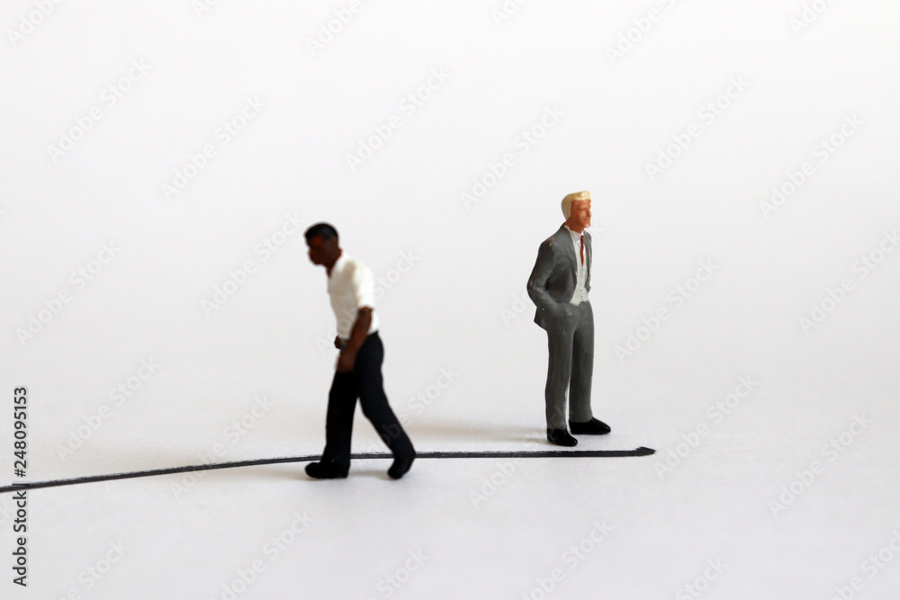 The concept of racial conflict. A miniature black man and a miniature white man standing back from each other with boundaries between them. The concept of racial conflict. A miniature black man and a miniature white man standing back from each other with boundaries between them.