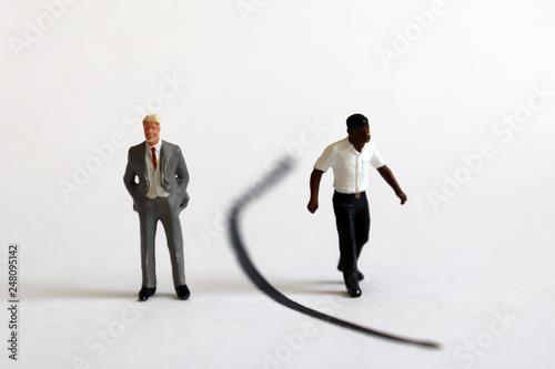 A miniature white man and a miniature black man standing between the boundaries.