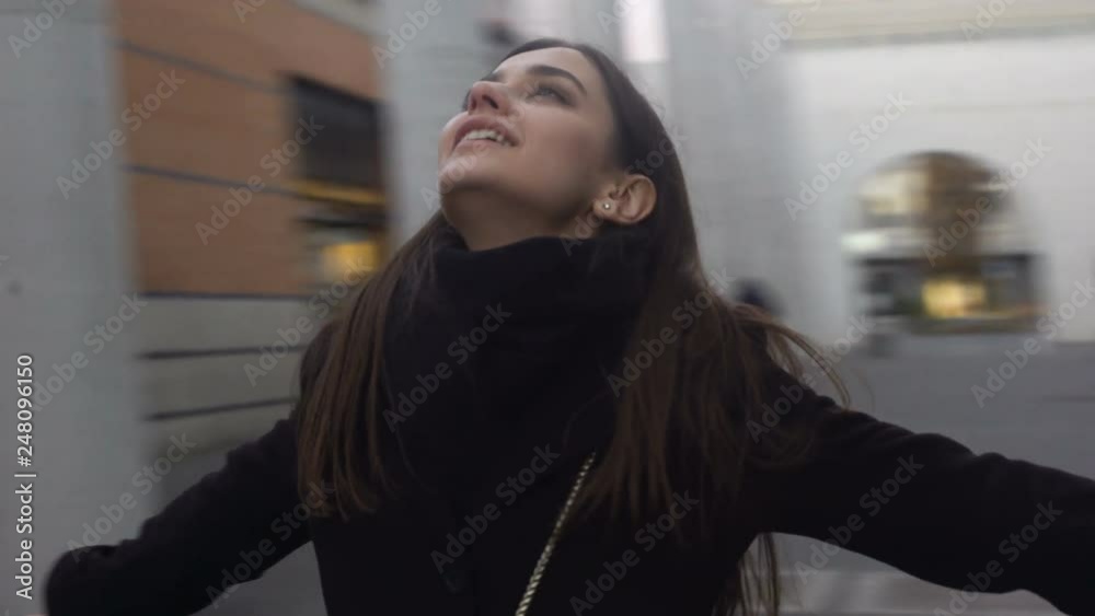 Happy woman standing on street, stretching hands looking up, inspiration concept Happy woman standing on street, stretching hands looking up, inspiration concept