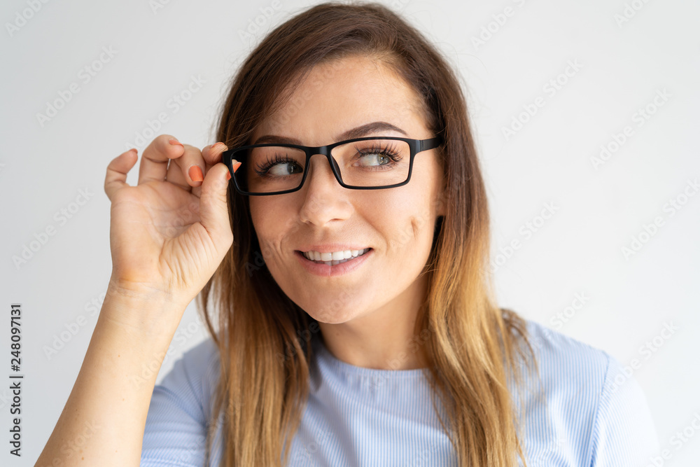 Curious pretty woman adjusting glasses and looking away Curious pretty woman adjusting glasses and looking away