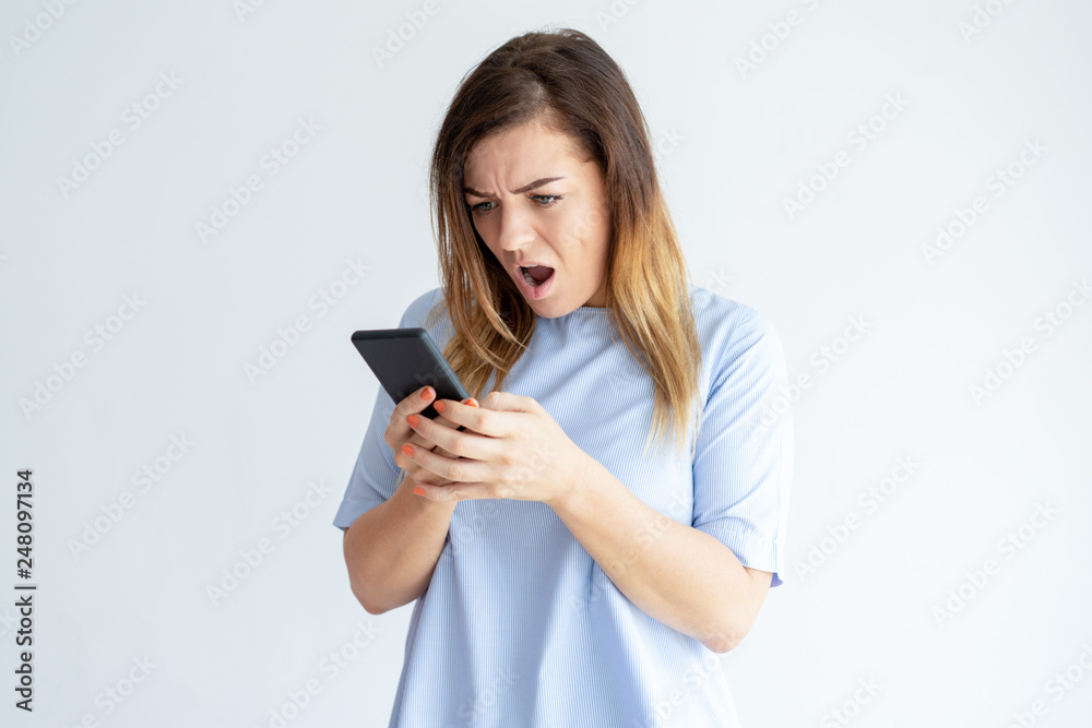 Disappointed woman looking at smartphone screen Disappointed woman looking at smartphone screen