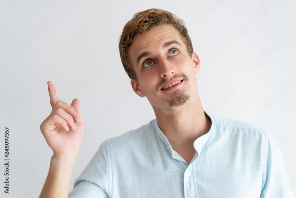 Smiling man pointing finger and looking upwards Smiling man pointing finger and looking upwards