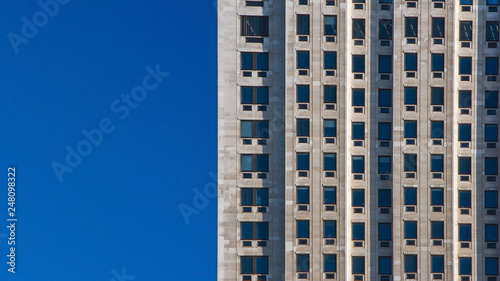 Regular pattern made of rectangular windows on block of flats / offices building. Clear sky (place for text) on left side. © Lubo Ivanko