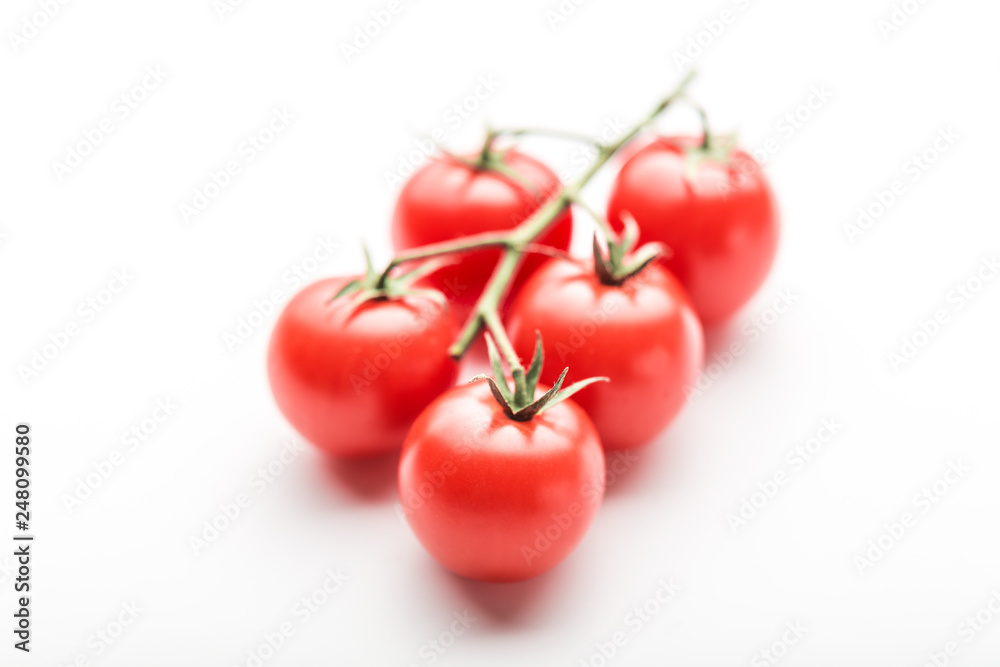 A branch of cherry tomato lies on a white surface. A branch of cherry tomato lies on a white surface.