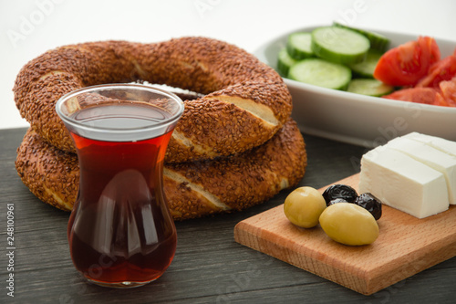 Turkish breakfast on black wooden table, black tea, bagels, olives, cheese, cucumber and tomatoes.