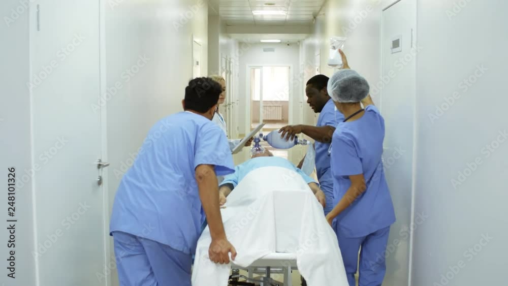 Following dolly shot of emergency room nurses administering oxygen and ...