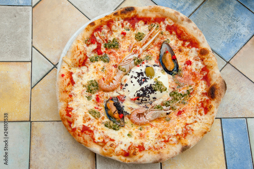 Delicious seafood pizza with prawns and mussels on colorful table in Ljubljana cafe, Slovenia