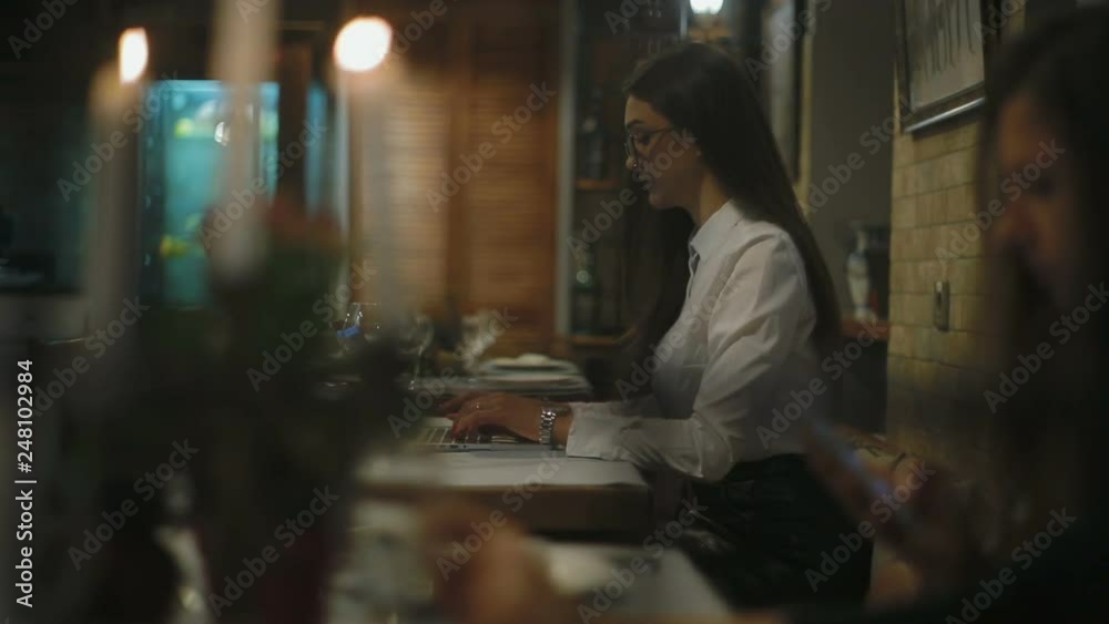 slow motion behind blurry image pretty girl in glasses sit at table with wine glass working on laptop in cafe slow motion behind blurry image pretty girl in glasses sit at table with wine glass working on laptop in cafe