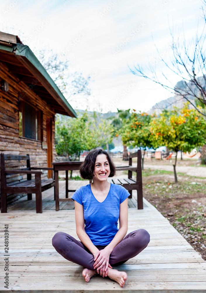 A woman is sitting on the porch of an old wooden house. A woman is sitting on the porch of an old wooden house.