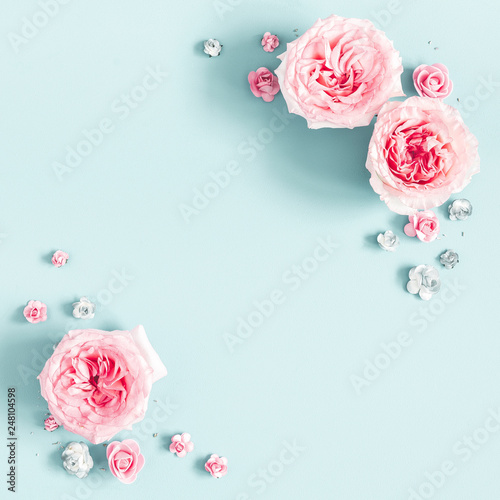 Flowers composition. Frame made of rose flowers on pastel blue background. Valentines day, mothers day, womens day, spring concept. Flat lay, top view, copy space, square
