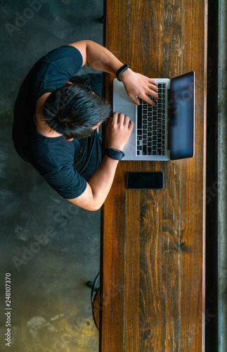 Top view of young Asian man working on laptop