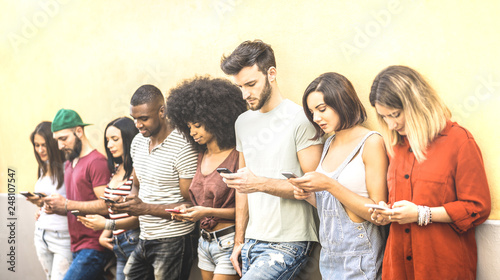 Multiracial friends using mobile smartphone at university coampus - Millenial people addicted by smart phones - Tech concept with always connected millennials on social networks - Bright warm filter photo