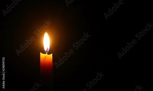 Obraz na plátně Yellow candle light burn against black background