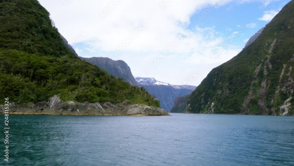 Shot from boat sailing past overgrown slopes of mountain ranges standing in ocean and forming island Shot from boat sailing past overgrown slopes of mountain ranges standing in ocean and forming island
