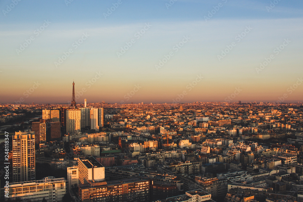 Obraz premium Eiffel tower between buildings in the last rays of the sun. Aerial view of Paris, France