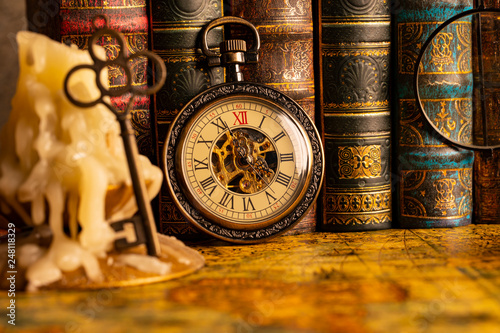 Antique clock on the background of vintage books. Mechanical clockwork on a chain.