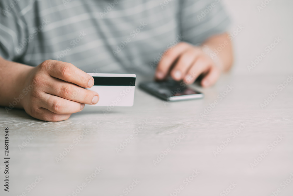 Cropped picture of man with credit card white pattern and phone Cropped picture of man with credit card white pattern and phone