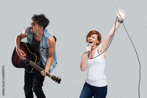 Musical artists sing and play acoustic guitar. Contemporary cover band. Isolated over grey background. Woman with microphone sing loudly 