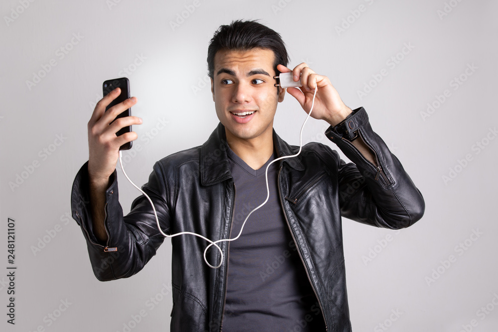 a young man in a black leather jacket charges your cell phone from the head. the concept of the new technology a young man in a black leather jacket charges your cell phone from the head. the concept of the new technology