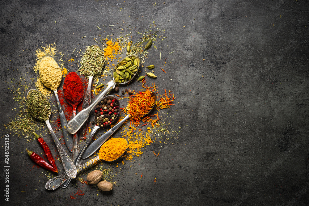Set of various spices on black stone background.