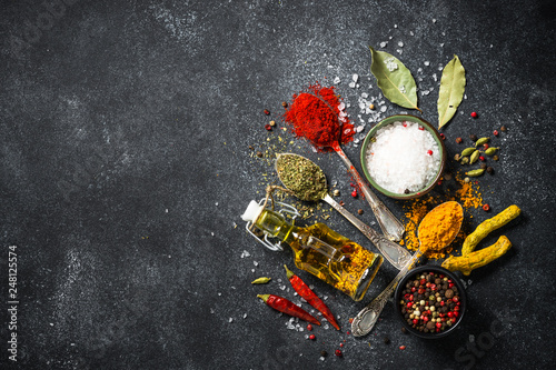 Spices and olive oil on black stone background.