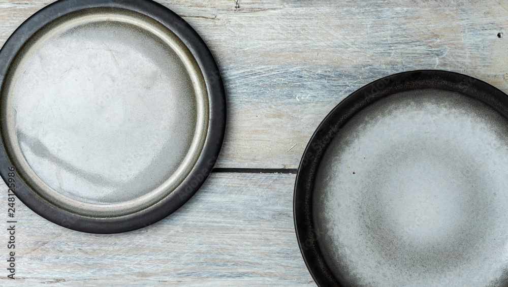 top view on white, wooden table top with two empty gray and white plates top view on white, wooden table top with two empty gray and white plates