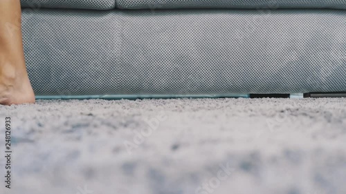 Women's legs are walking on a gray carpet that is on the floor. Fluffy carpet from above. Modern style.