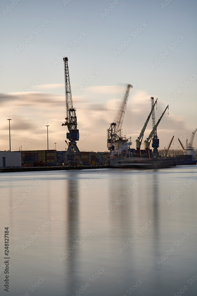 Cranes at work loading and unloading ships at the Port of Rotterdam Cranes at work loading and unloading ships at the Port of Rotterdam