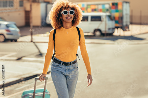 Billede på lærred Cheerful woman traveller walking on street