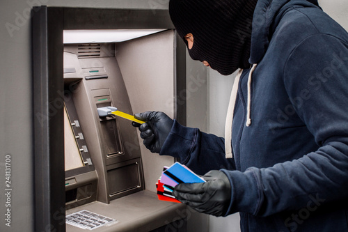 Thief. Hacker stealing money from ATM machine. Phishing, ATM skimming