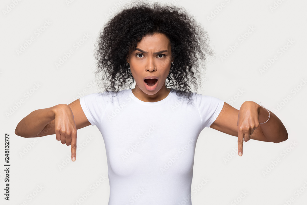 Shocked black woman looking at camera pointing fingers below Shocked black woman looking at camera pointing fingers below