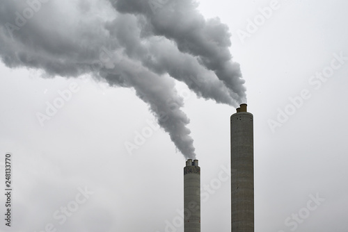 Chimney of a factory blowing greenhouse gas emissions in the air 