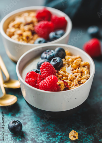 Vegetarian breakfast, a bowl with organic granola, fresh raspberries and blueberries and coconut yoghurt.