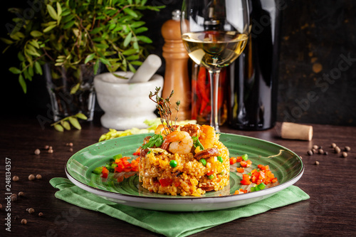 European Spanish cuisine. Paella with shrimps, chicken and coblas chorizo. White wine on the table. Closeup background image. Beautiful serving dishes in the restaurant. copy space