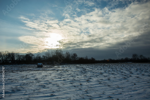 The sun setting behind the cloud and snow in the field © darekb22