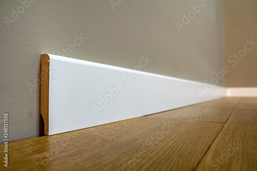 Konstfotografi Wooden or plastic white floor plinth installation in big empty room on wooden floor and white plastered stucco walls background