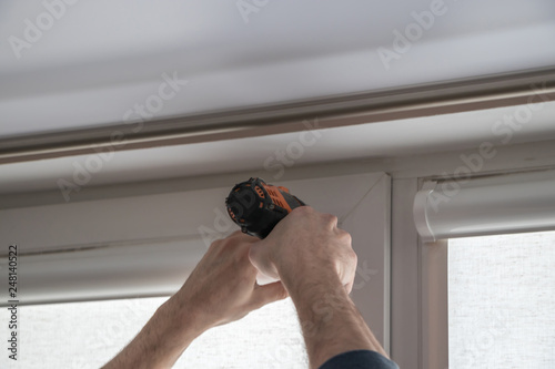 worker mounts roller blinds on window frames