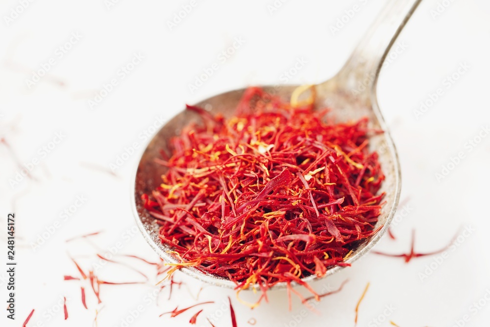 Fototapeta premium Saffron threads in a rustic spoon isolated on white