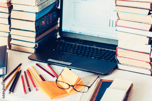 Laptop, stack of books, notebooks and pencils on white table, education office concept background.