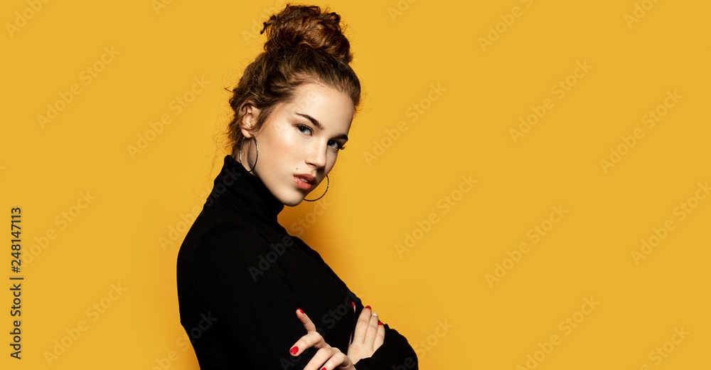 Portrait of beautiful girl posing for fashion photoshoot on yellow  background. Pretty model dressed in stylish black pullover. Trend and  lifestyle concept Stock Photo | Adobe Stock