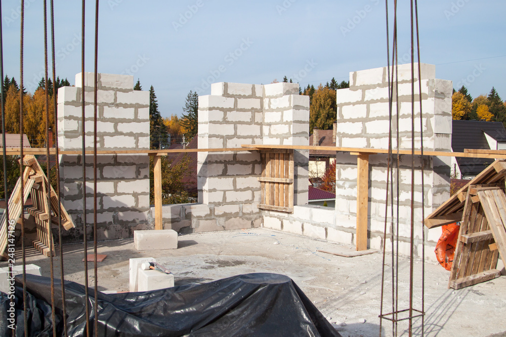 Fototapeta premium view of laying walls of first floor, fittings for filling supporting columns. Construction of country house made of foam blocks